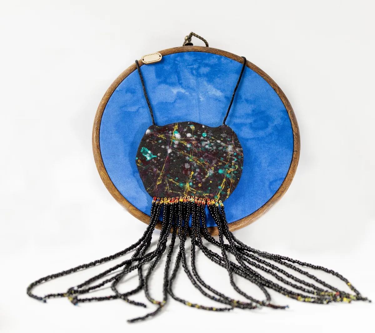 Pendentif en tissu wax bleu avec médaillon peint à la main et franges de perles noires