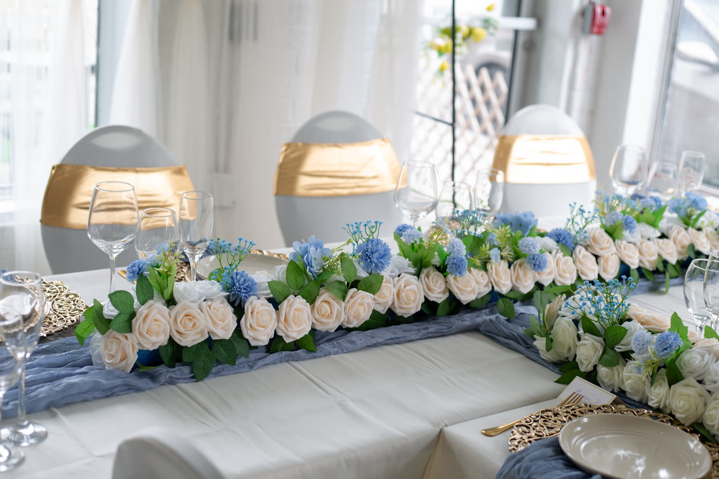 Longue table dressée avec vaisselle dorée et fleurs